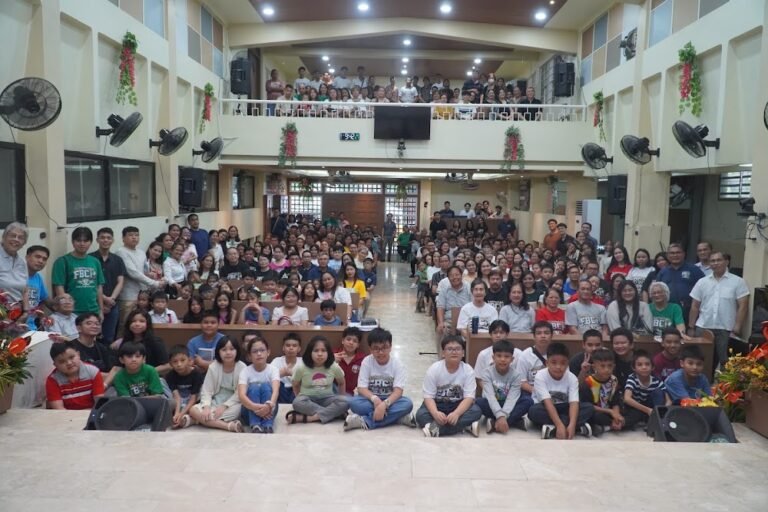 A full church hall of families and young people smiling at the camera